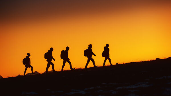 five persons walking at sunset