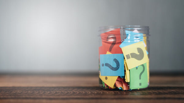 colorful paper with question mark in a plastic jar on wooden table